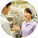 食品工場の作業ラインで担当者と話す日本人女性コンサルタント
